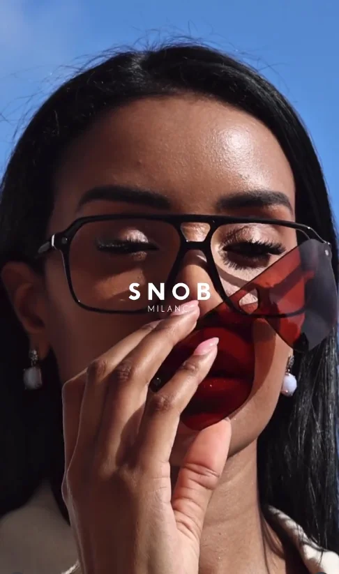 Mulher a retirar um clipe de sol de lente vermelha de uma armação Snob Milano